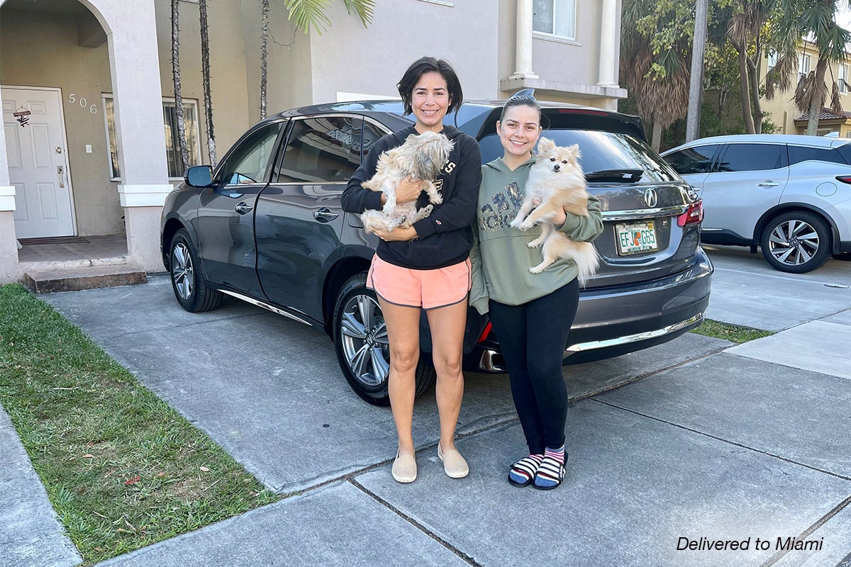 Smiling women with dogs have their car delivered