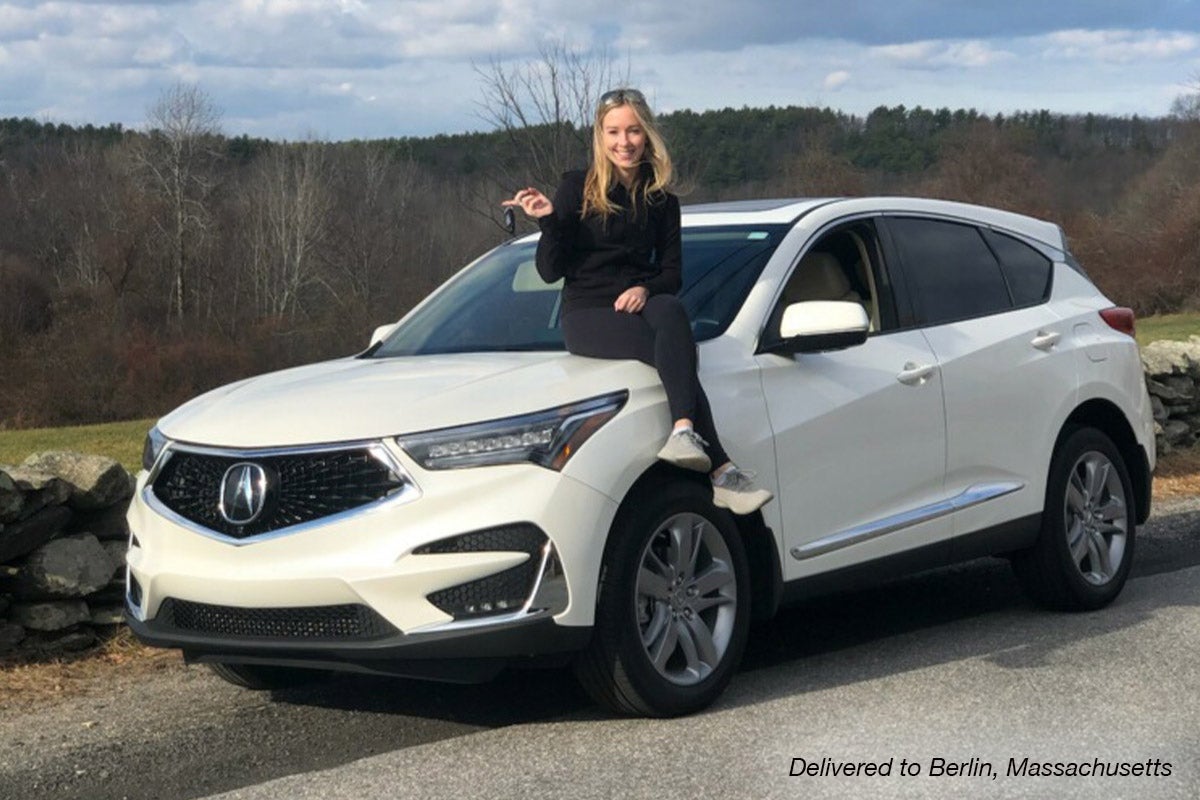 Woman sitting on the hood of her new white Acura MDX